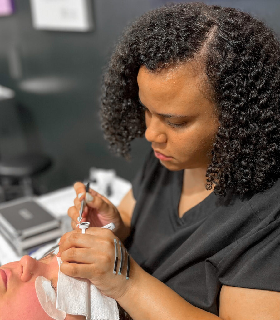 esthetician student at the salon professional academy in Dallas doing eyelash extensions